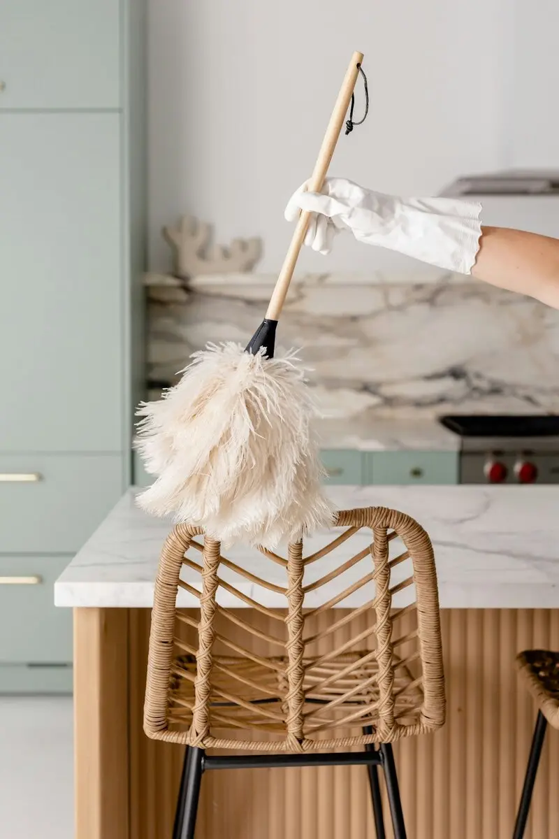 Cleaner dusting a kitchen light fixture